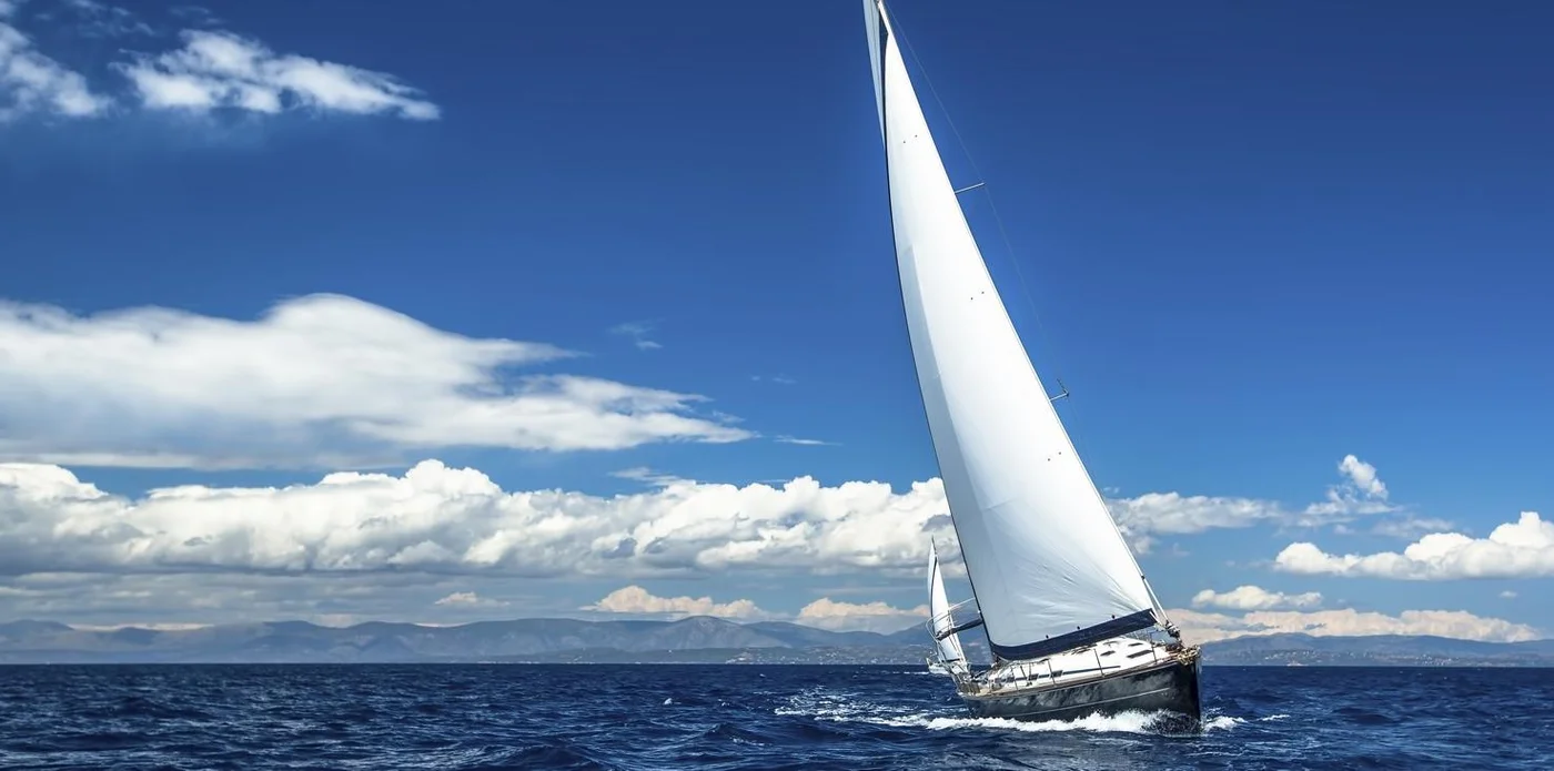 Segelyacht unter weißem Segel auf ruhigem Meer mit blauem Himmel